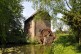 Foto: Mühlengebäude aus Backstein mit Mühlrad und Mühlteich.